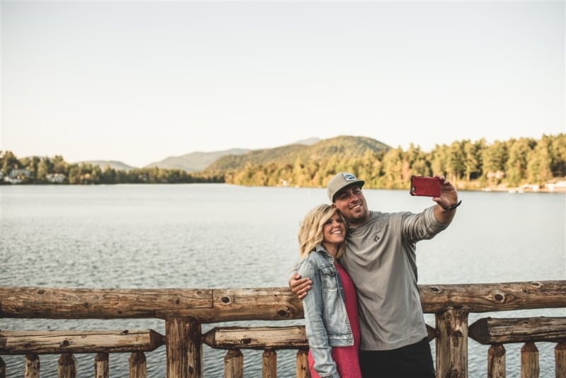Perfect selfie spot on the boathouse couple taking a selfie on the boathouse with mountain backdrop