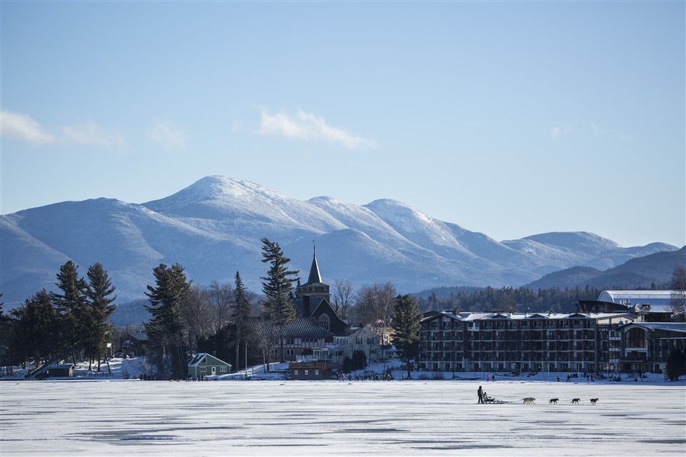 the golden arrow hotel exterior with mountain backdrop. Dogsled on Mirror lake