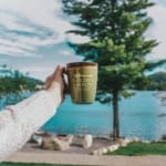 person holding Golden Arrow mug with views of Mirror Lake