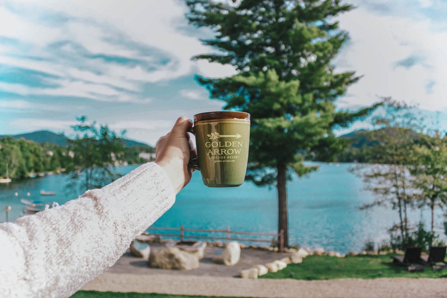 person holding Golden Arrow mug with views of Mirror Lake