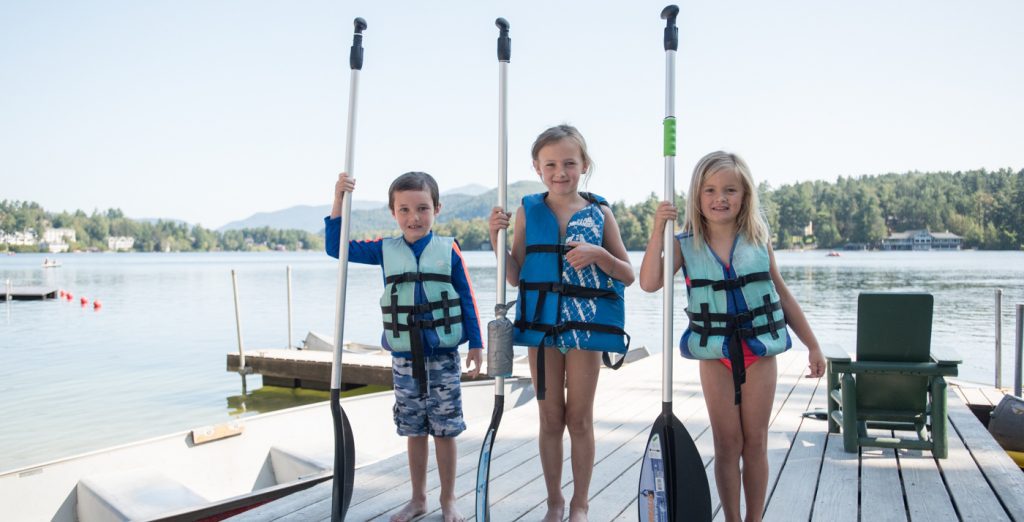 3 kids in lifejackets with paddles