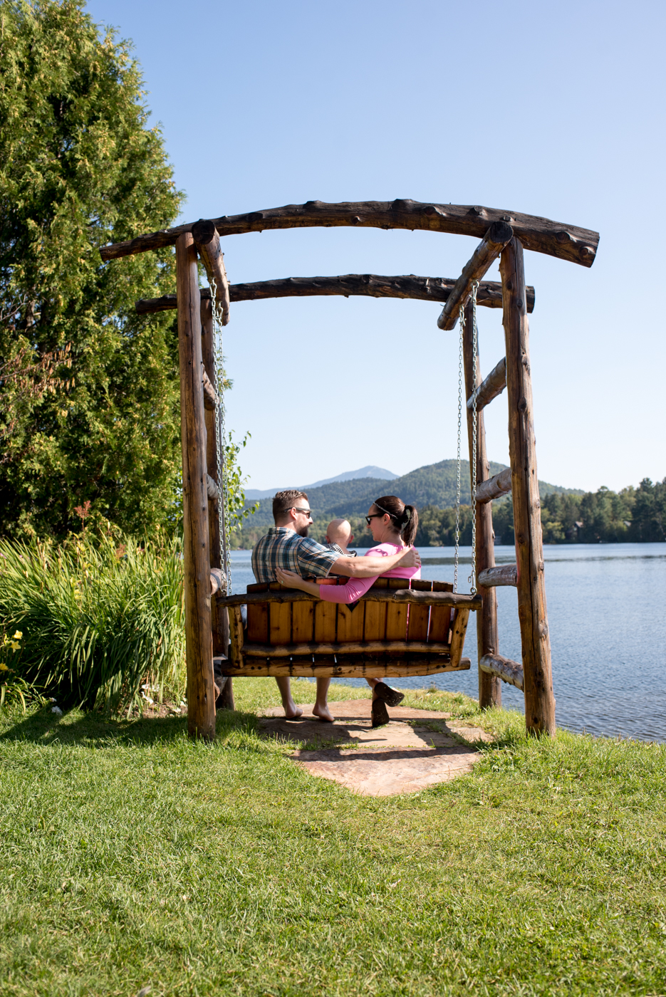 family sitting on wooden bench swing