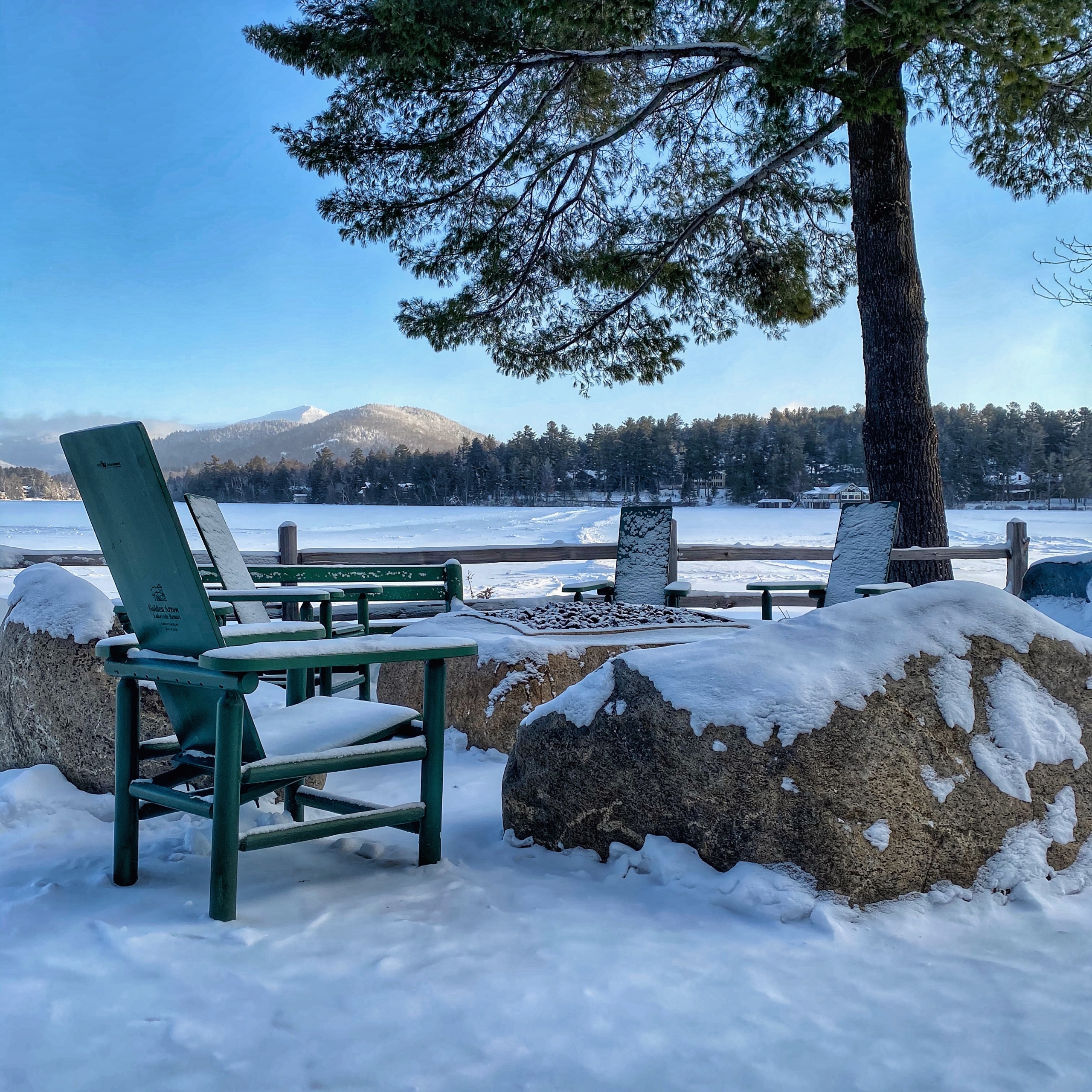 Winter firepit and Adirondack chairs covered in snow