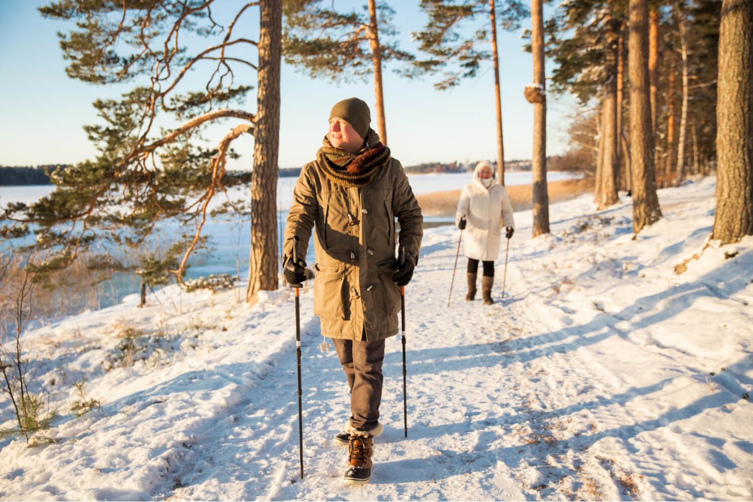 A pair of hikers traverse a trail while walking along Lake Placid during a late-winter vacation.