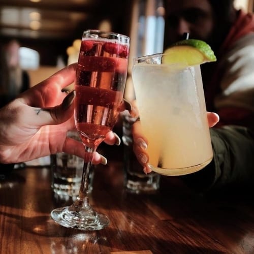 Glass of wine and cocktail being toasted together