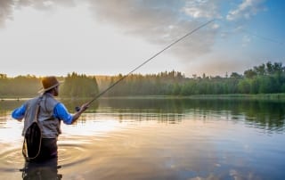 Man standing in river doing Adirondack fishing