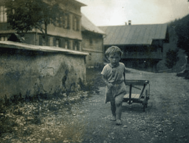 4 year old Wini in Balderschwang pulling a cart down an unpaved street